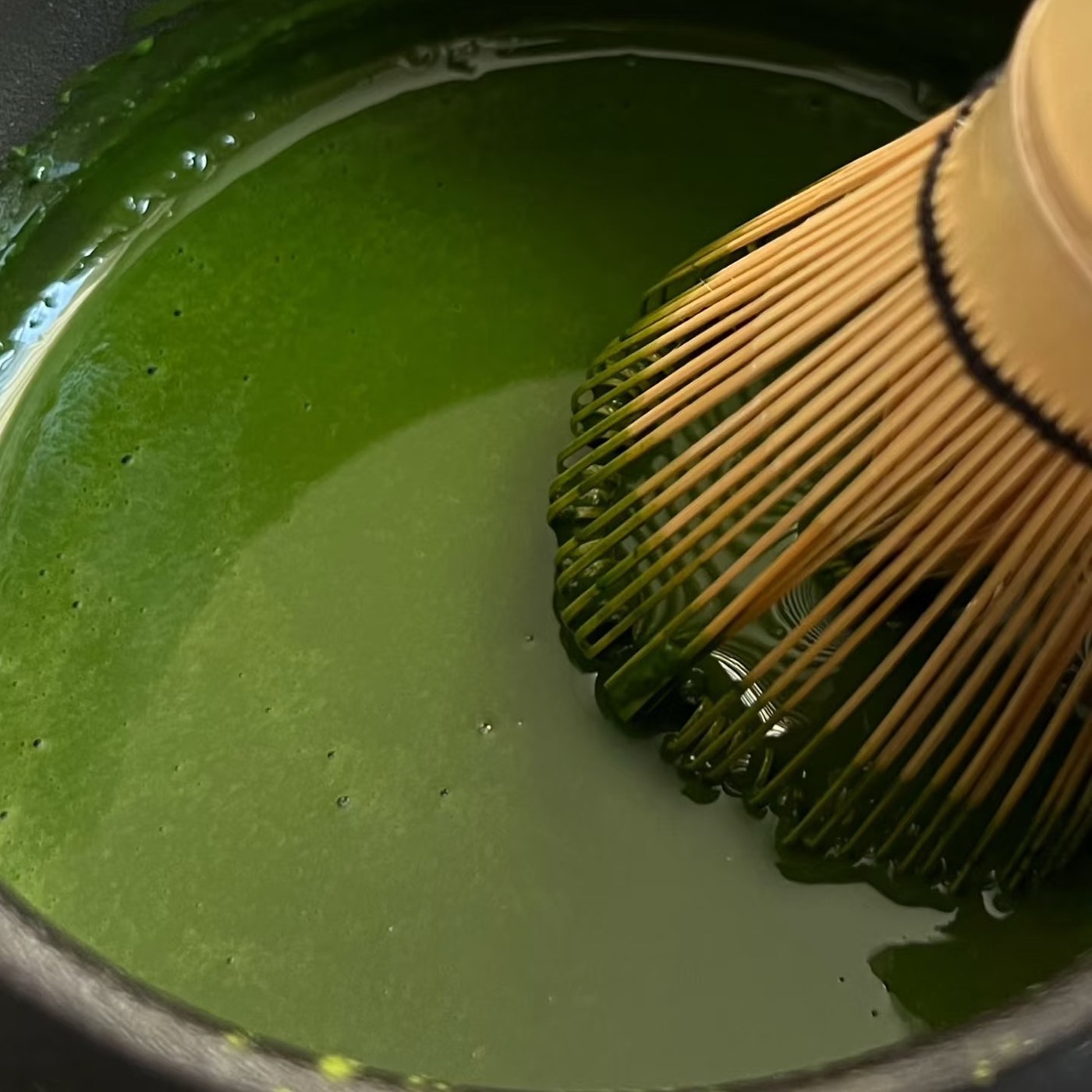 Fouet en bambou chasen émulsionnant un matcha vert dans un chawan